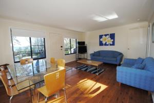 a living room with a blue couch and a glass table at Beachfront Unit - Belle Escapes Jervis Bay in Vincentia