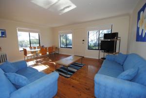 ein Wohnzimmer mit zwei blauen Sofas und einem Tisch in der Unterkunft Beachfront Unit - Belle Escapes Jervis Bay in Vincentia + 7 Fotos