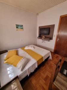 um quarto com uma cama e uma televisão na parede em CASA DO PINHEIRO 2 em Chapecó