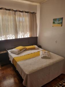 um quarto com uma cama com lençóis amarelos e uma janela em CASA DO PINHEIRO 2 em Chapecó