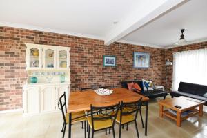 sala de estar con pared de ladrillo, mesa y sillas en Excellent Location - Belle Escapes Jervis Bay, en Vincentia