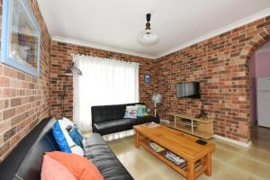 a living room with a couch and a brick wall at Excellent Location - Belle Escapes Jervis Bay in Vincentia