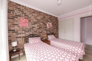 a bedroom with two beds and a brick wall at Excellent Location - Belle Escapes Jervis Bay in Vincentia
