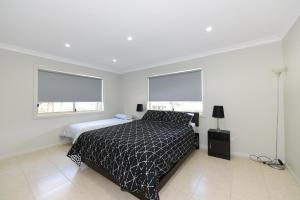 a bedroom with a bed and two windows at Paradise Beach House - Belle Escapes Jervis Bay in Sanctuary Point