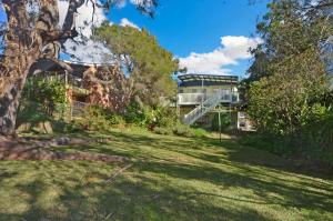 a house in the middle of a yard with trees at Pipers Run - Belle Escapes Jervis Bay in Vincentia