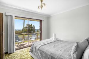 a white bedroom with a bed and a balcony at Nelsons Beach House - Belle Escapes Jervis Bay in Vincentia