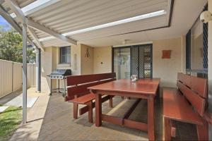 a patio with a wooden table and benches and a grill at Villa Serene - Belle Escapes Jervis Bay in Vincentia