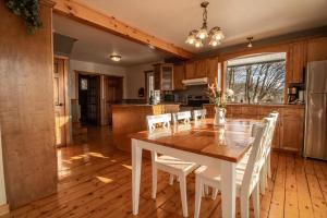 - une cuisine avec une table en bois et des chaises blanches dans l'établissement Les Chalets Tourisma - Maison de campagne avec spa - La Campagnarde, à Saint-Raymond