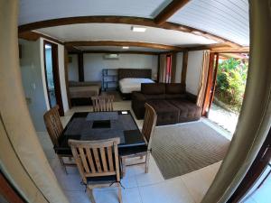 a room with a table and a couch and a bedroom at Chalé e Suite Manacá in Ubatuba