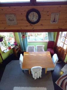 a dining room with a table and chairs and a clock at Casa de Lago y Montaña in El Calafate