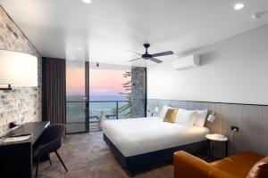 a hotel room with a bed and a view of the ocean at The Sebel Brisbane Margate Beach in Redcliffe