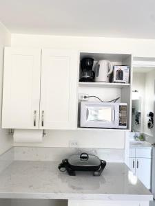a kitchen with white cabinets and a microwave at Hawaiian monarch cozy studio in Honolulu