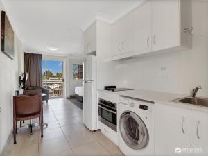a white kitchen with a washing machine and a sink at Studio 20 ENDEAVOUR INN in Emu Park