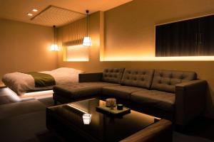 a living room with a couch and a bed at HOTEL ZEN-Adult Only in Hirosaki