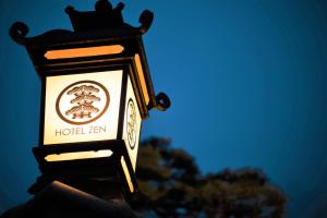 a sign for a hotel inn with a tree in the background at HOTEL ZEN-Adult Only in Hirosaki