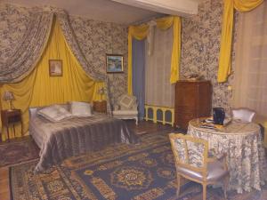 een slaapkamer met een bed en een tafel met een stoel bij Location meublé de tourisme La Rose des Fables in Château-Thierry