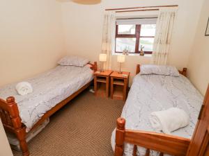 two twin beds in a room with a window at The Stables in Llandyfrydog