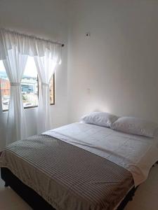 Schlafzimmer mit einem Bett mit Vorhängen und einem Fenster in der Unterkunft Excelente ubicación y acogedor apartamento in Manizales