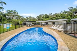 a swimming pool with chairs and a house at Haven Holiday Resort Sussex Inlet in Sussex inlet