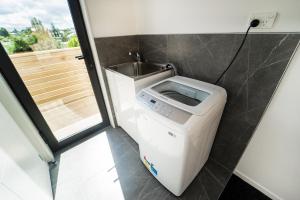 - un lave-linge dans la salle de bains pourvue d'un lavabo dans l'établissement Modern Howick Town House Fibre WiFi Netflix, à Auckland