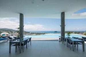 a patio with tables and chairs and a pool at The View Phuket in Kata Beach