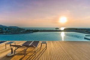 - une piscine avec une table et des chaises sur une terrasse au coucher du soleil dans l'établissement The View Phuket, à Kata Beach