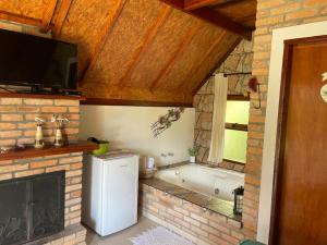 baño con nevera blanca y chimenea en Flor da Montanha, en Monte Verde