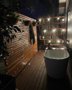 a bathroom with a tub and a wooden floor with lights at Ark-imedes - Unique float home on the Murray River in White Sands