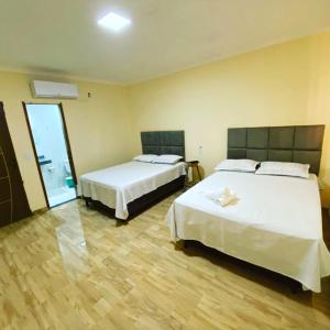 Habitación de hotel con 2 camas y espejo en Pousada vista alegre en Itaberaba