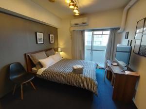 a bedroom with a bed and a television and a chair at Coco Fukuoka Chiyo in Fukuoka