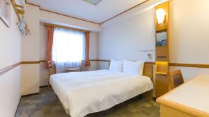 Toyoko Inn JR Wakayama eki Higashi guchi في واكاياما: غرفه فندقيه سرير ابيض ونافذه