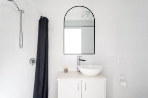 a white bathroom with a sink and a mirror at Burleigh Gold Coast Motel in Gold Coast