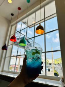 a hand holding a drink in front of a window at LOOK UP CAFE INN in Siem Reap