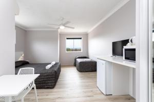 a white living room with a bed and a table at Burleigh Gold Coast Motel in Gold Coast