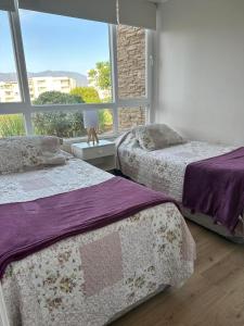 a bedroom with two beds and a large window at Haydeé Lomas de Papudo IV in Papudo