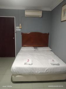 a bedroom with a bed with white sheets and slippers at BASE HOTEL in Kuala Kubu Bharu