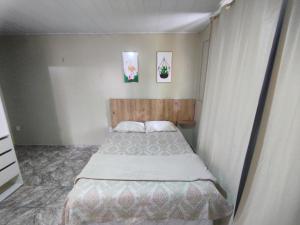 マナウスにあるCasa espetacular próximo ao Museu da Amazôniaの小さなベッドルーム1室(ベッド1台付)が備わります。壁に2枚の絵が飾られています。