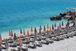 un mucchio di sedie e ombrelloni su una spiaggia di Apartment Beautifull View a Rabac