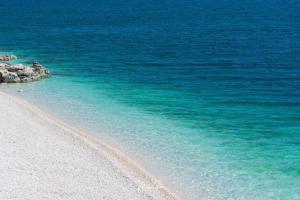 una spiaggia con acqua blu e impronte di piedi nella sabbia di Apartment Beautifull View a Rabac