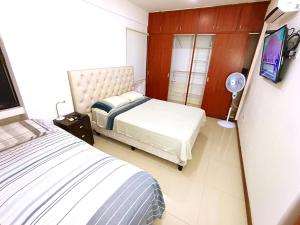 1 dormitorio con 2 camas y TV. en Departamentos en Edificio Acrebol Santa Cruz en Santa Cruz de la Sierra