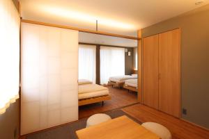 a bedroom with two beds and a table and chairs at Neon Hotel in Kanazawa