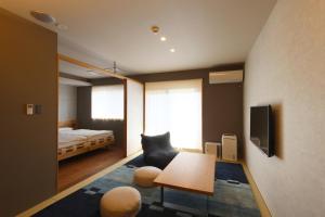 una sala de estar con una cama y una habitación con una mesa. en Neon Hotel, en Kanazawa