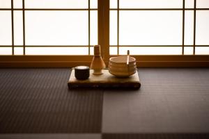 a table with two bowls and two cups on the floor at HOTEL ZEN-Adult Only in Hirosaki