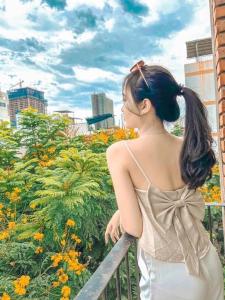 una mujer de pie en una valla mirando flores en Anstay Homestay & Apartment en Da Nang