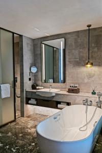 een badkamer met een groot bad en een wastafel bij LN Dongfang Hotel, Pazhou in Guangzhou