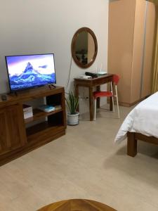 Zimmer mit einem TV, einem Bett und einem Spiegel in der Unterkunft DeckBett Stay in Manila
