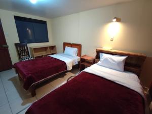 um quarto de hotel com duas camas com lençóis vermelhos em Casa particular em Arequipa