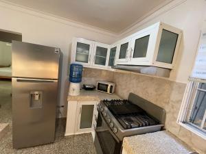 a kitchen with a stainless steel refrigerator and white cabinets at Apartamento calido in Santo Domingo