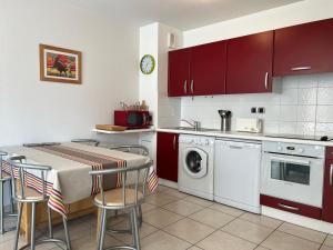 eine Küche mit roten Schränken und einem Tisch mit Stühlen in der Unterkunft Appartement Ciboure, 3 pièces, 4 personnes - FR-1-239-895 in Ciboure