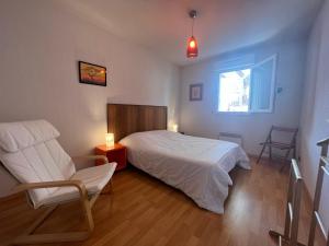 ein Schlafzimmer mit einem Bett, einem Stuhl und einem Fenster in der Unterkunft Appartement Ciboure, 3 pièces, 4 personnes - FR-1-239-895 in Ciboure